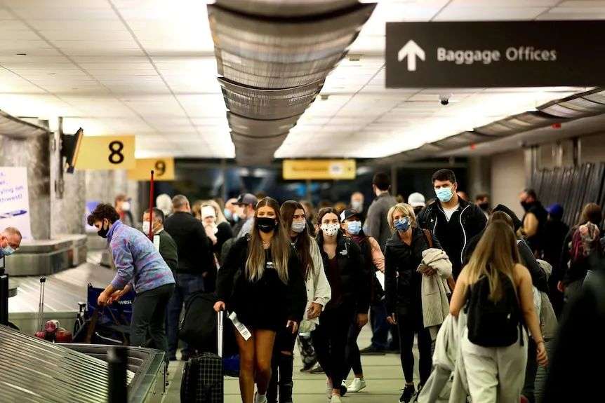 Travellers pick up luggage at a baggage carousel in an airport.