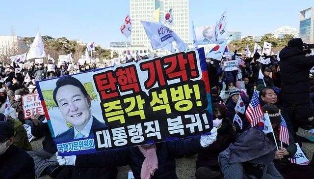 2025年2月22日，韩国大田广域市，尹锡悦的支持者在大田市政府前的公园挥舞国旗和标语牌。图片来源：视觉中国