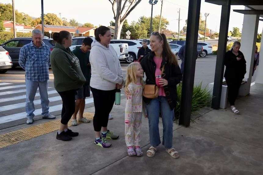 A crowd of people lining up outside a doctor's clinic