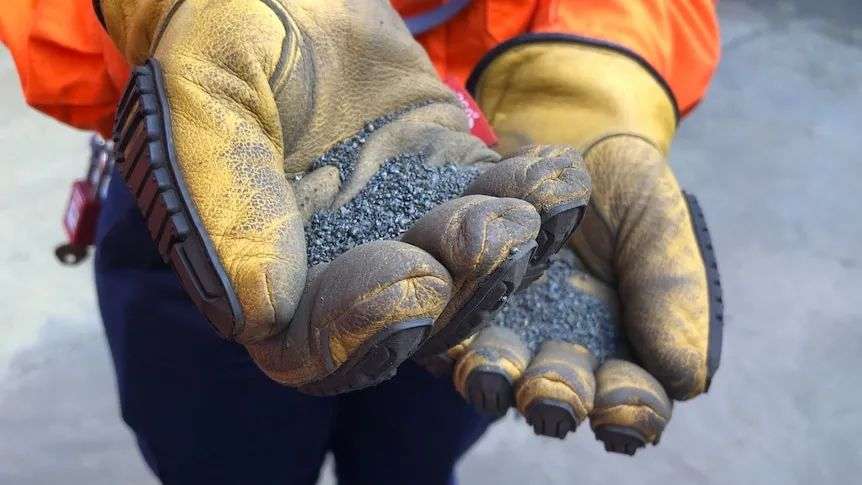 A person holds a handfull of ground nickel