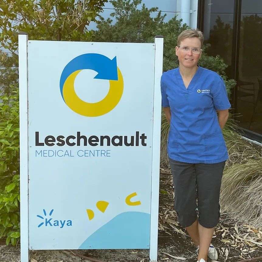 A middle aged woman with short brown hair and blue scrubs