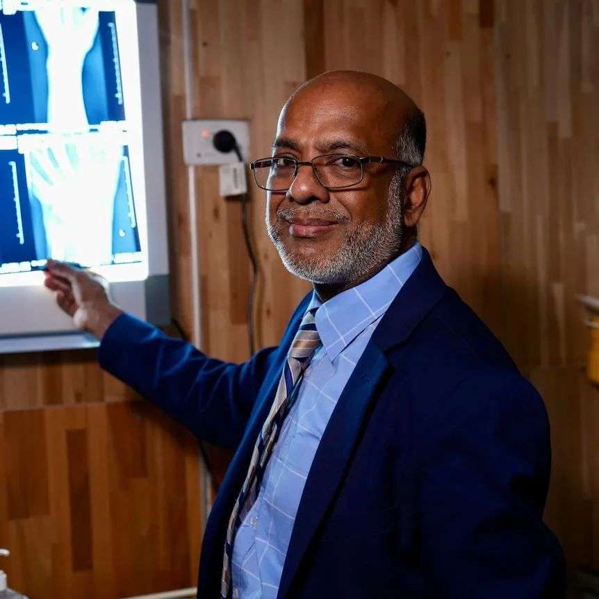 A middle aged black doctor standing in front of an x ray