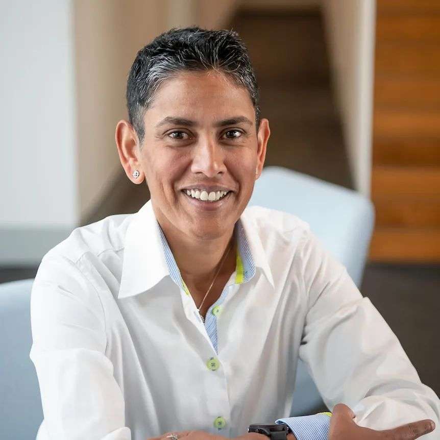 A middle-aged woman of colour with short black hair and a white shirt