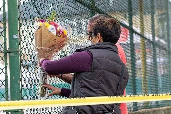 Members of the public attach flowers to a fence, near the scene where a vehicle drove into crowd at a street festival the night before.