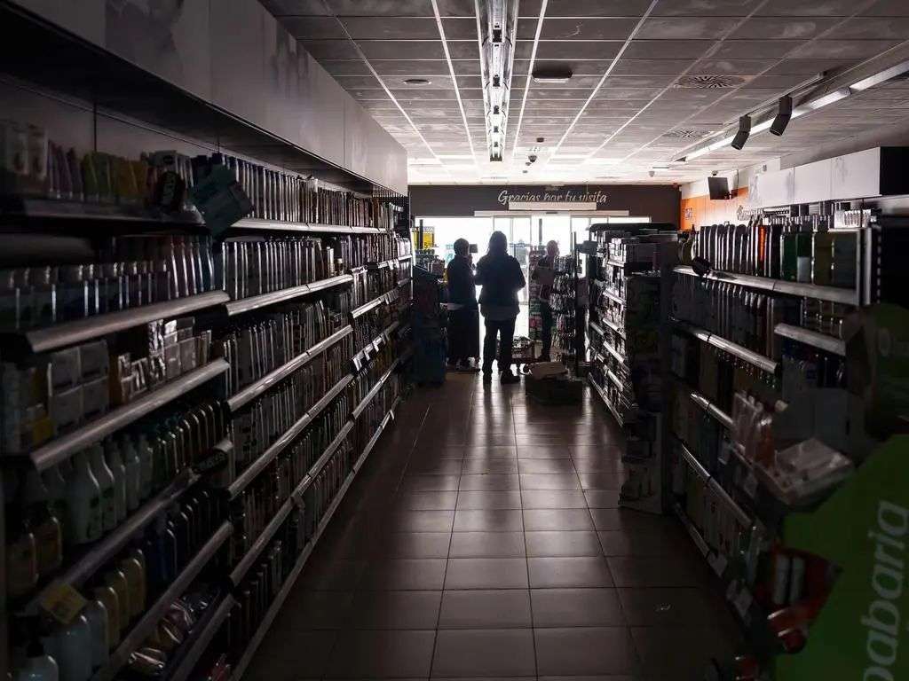 Employees stand inside a supermarket plunged into darkness in Burgos during the massive power cut affecting the entire Iberian Peninsula. Picture: AFP