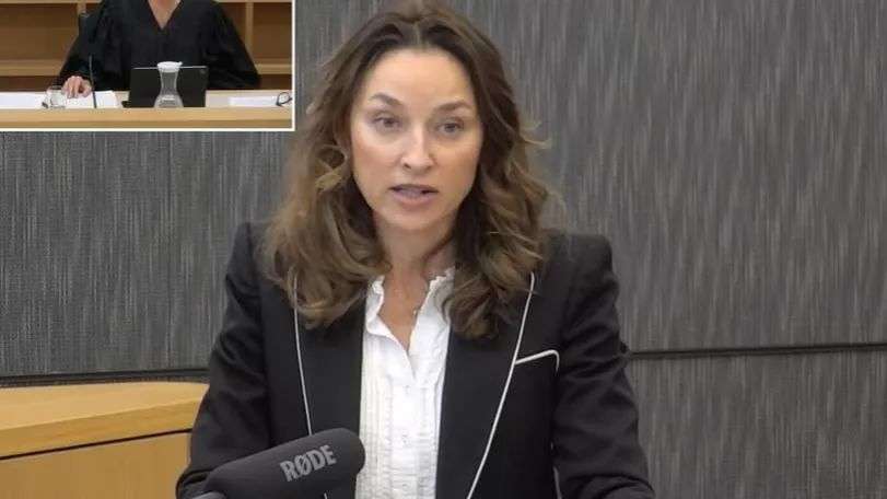Woman stands in courtroom, woman in road in top left-hand corner