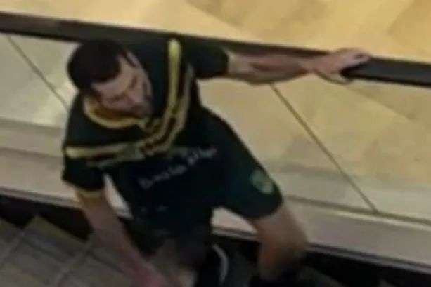 A poor quality photo of a man with a knife on an escalator, taken from above.