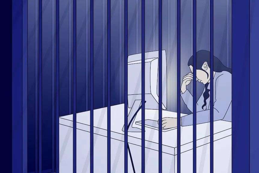 A person sits at a computer desk behind bars, their head resting on one hand, lit up by the screen