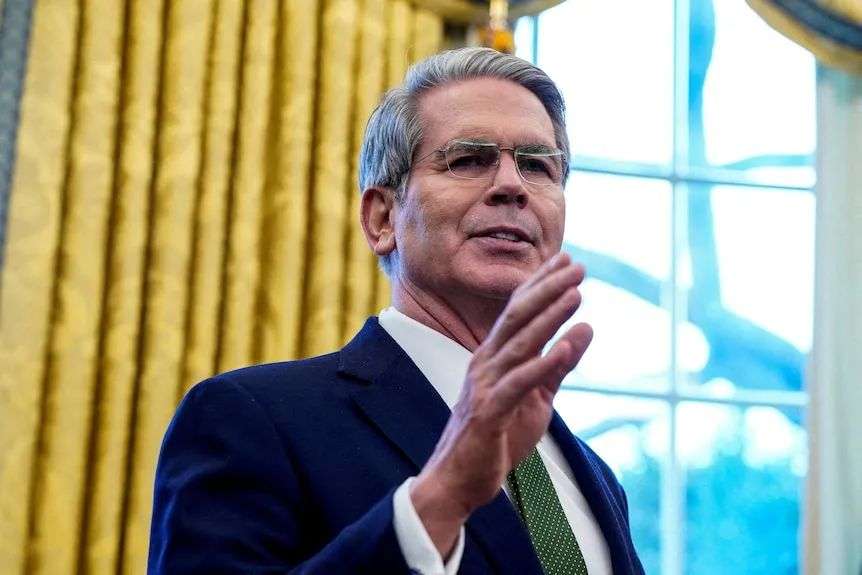 Scott Bessent speaks at the White House with his hand in the air.