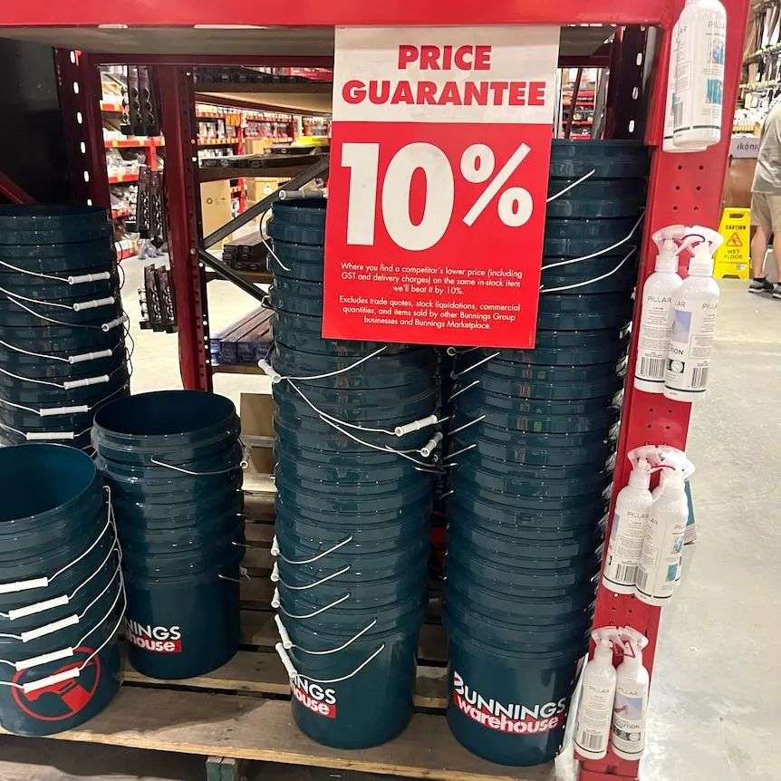 Dozens of Bunnings branded buckets sitting on a shelf. In front of them is a 'Price Guarantee 10%' sign.