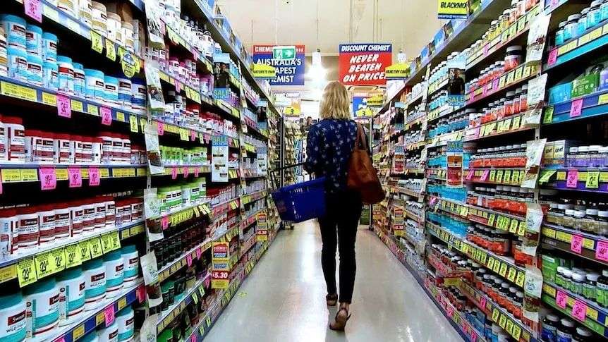 A woman walks down the aisle of a chemist