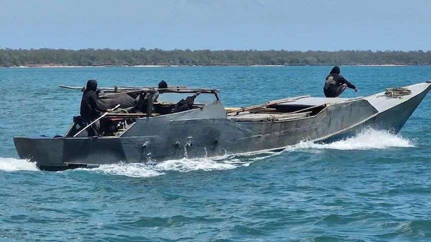 A close-up shot of a boat with three people dressed in black on board.
