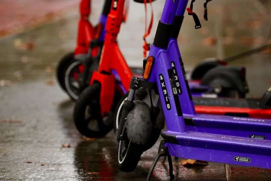 A cllose-up shot of the front wheels and decks of some e-scooters in Perth.
