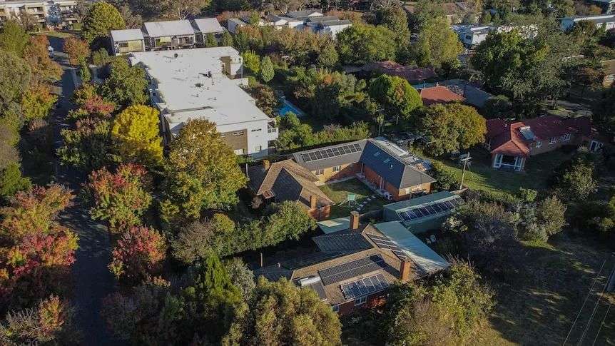 A drone view of a big housing complex in Canberra with rooftop solar cells on the roofs.