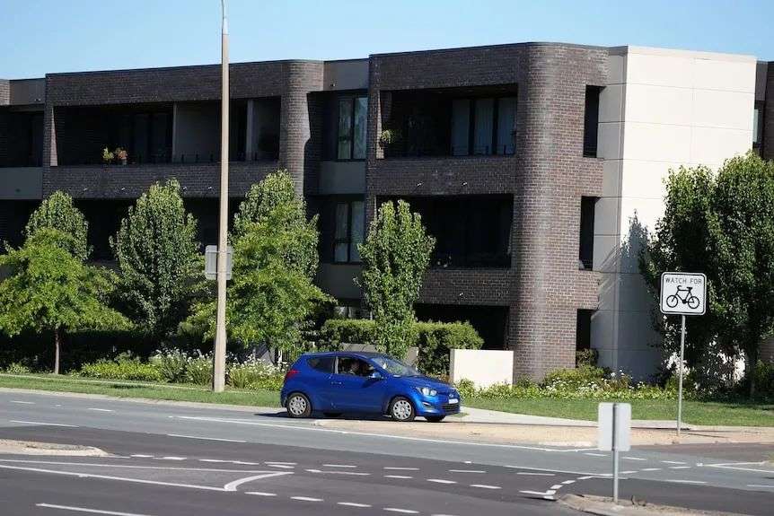 A modern three-story housing block with a road in the front.