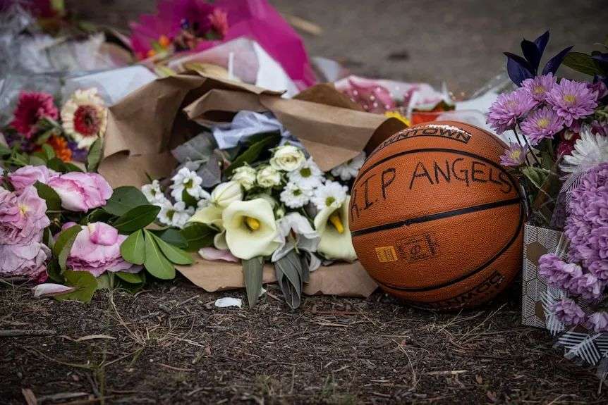 A close up of bunches of flowers on the ground and a basketball upon which someone has written 