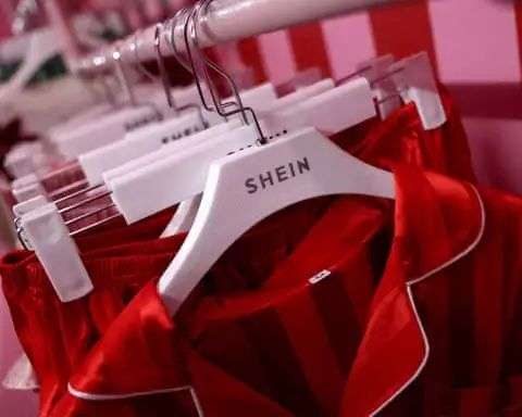 A clothes rail of red satin-like Shein pyjamas hanging from clothes hangers with the fast fashion company’s lego