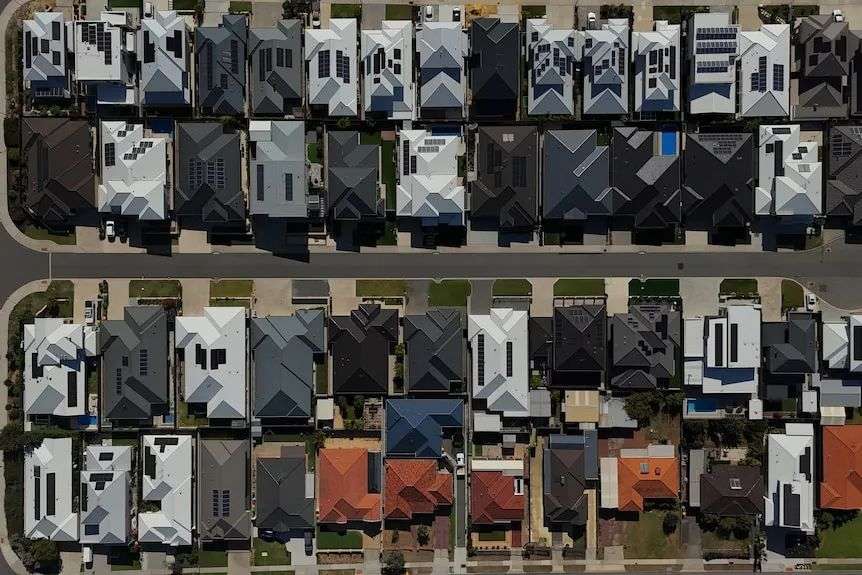 Drone shot looking directly down at sea of household rooftops with solar panels