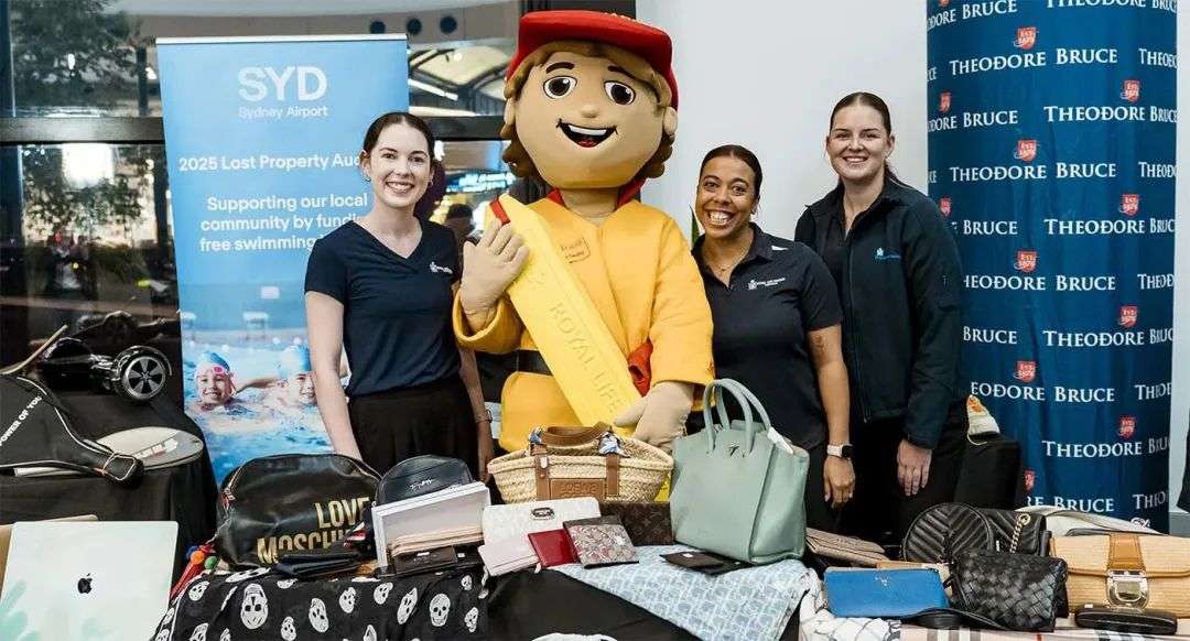 Staff stand with a life saver mascot behind a table filled with items for the airport's Lost Property Auction.