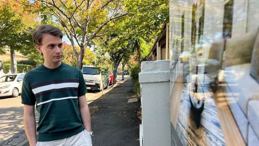 Jordan looking at a real estate sign out front of a house.