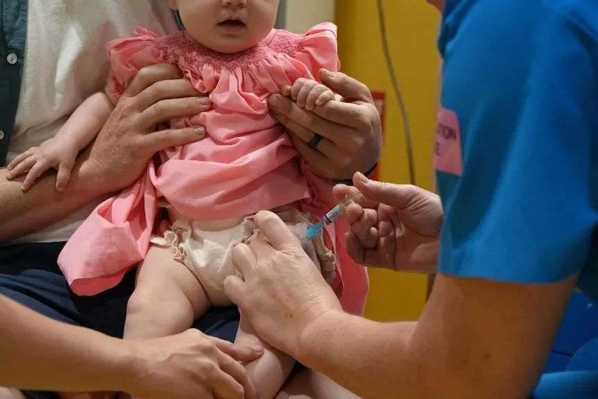 A needle going into a baby's thigh.