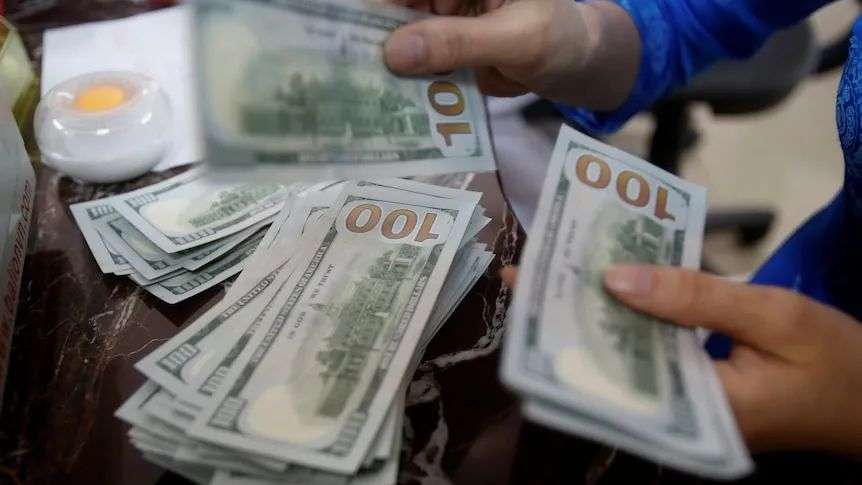 The hands of a person counting through piles of $100 US dollar notes