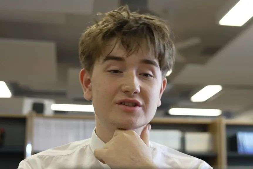 A young white boy with short brown hair looking at a screen in a classroom