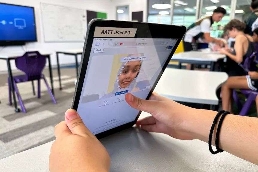 A child's hands hold a tablet in a classroom