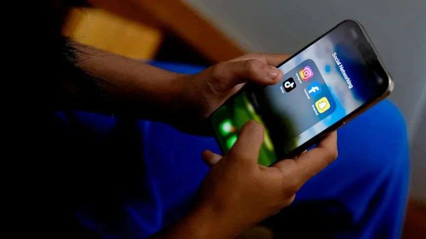 A high school student poses with her mobile showing her social media applications.
