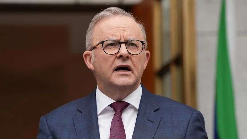 Anthony Albanese in a suit and tie speaks in a courtyard.
