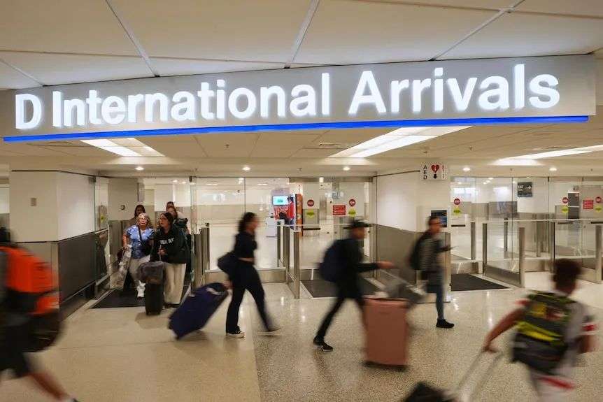 Passengers at the arrival gates of an airport, carrying their hand luggage.