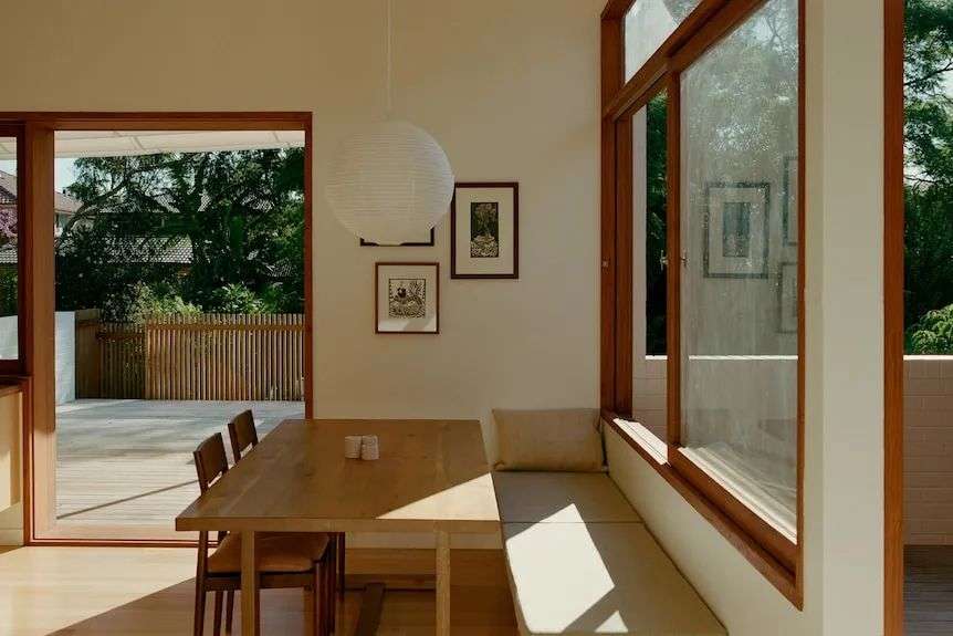 a light-filled dining room with timber framed windows opens onto a patio