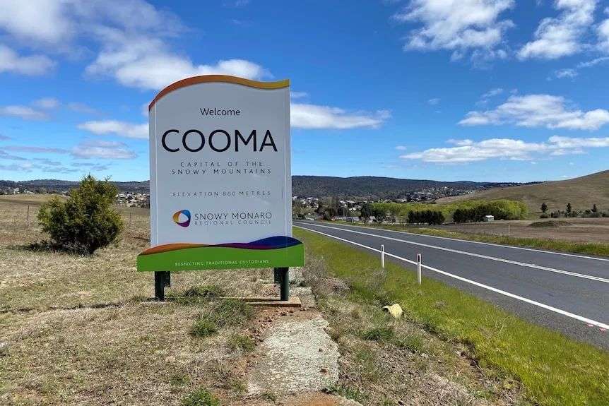 a sign of cooma next to a road