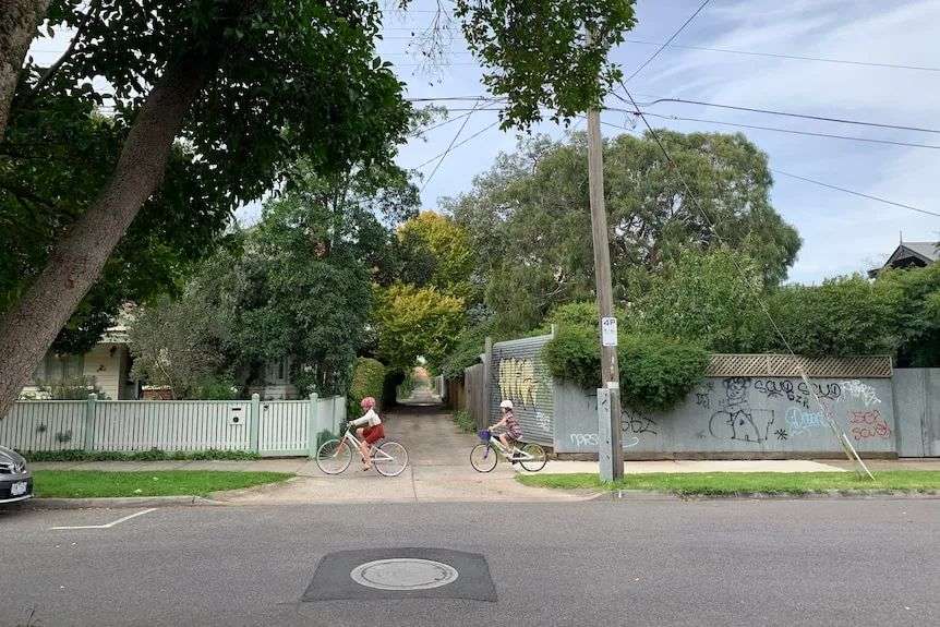 An alley with a high fence and graffiti.
