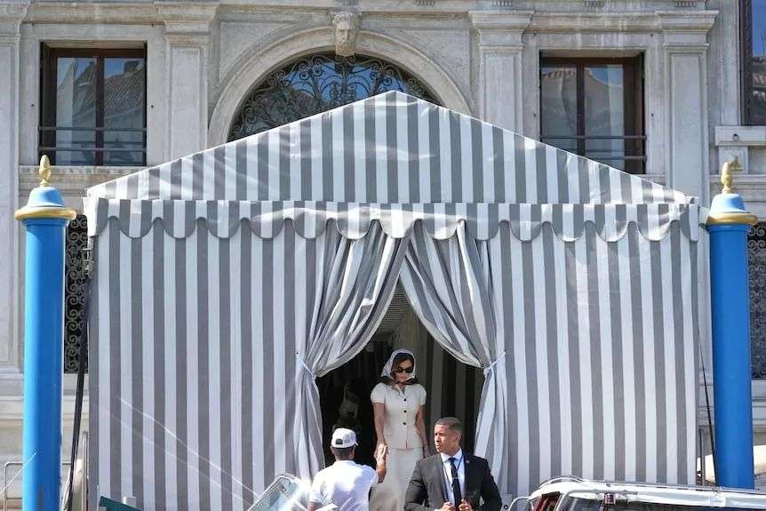 A woman walks through a striped tent.