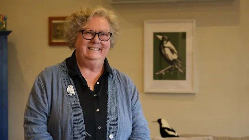 Sandie standing in her living room surrounded by magpie themed knick knacks