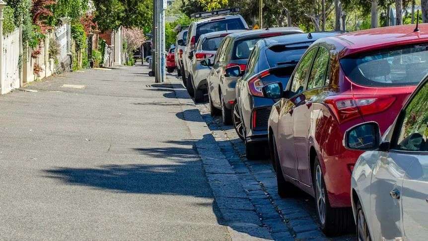 A residential Melbourne street with a row of parked cars.