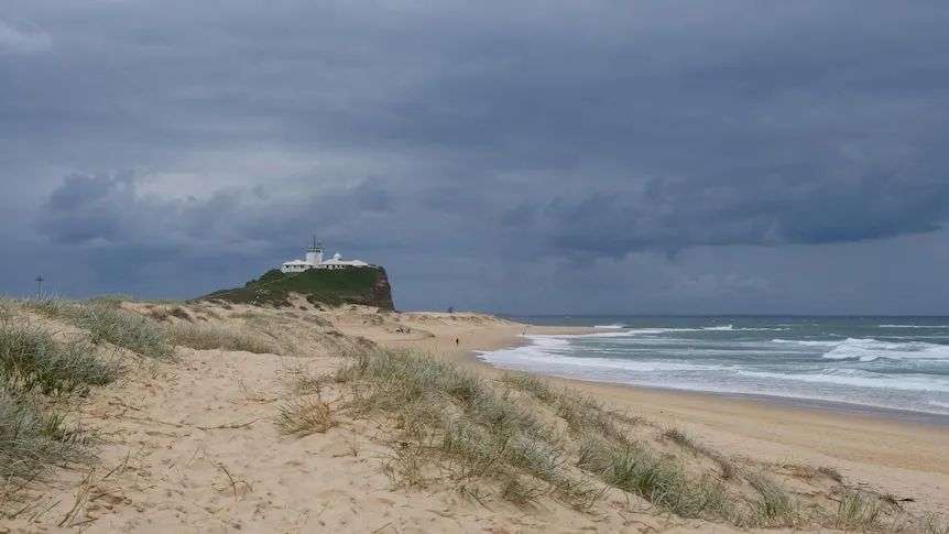 Stormy clouds hang over newcastle's nobbys beach and lighthouse