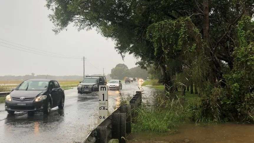 Cars on wet road with body of grey water to left