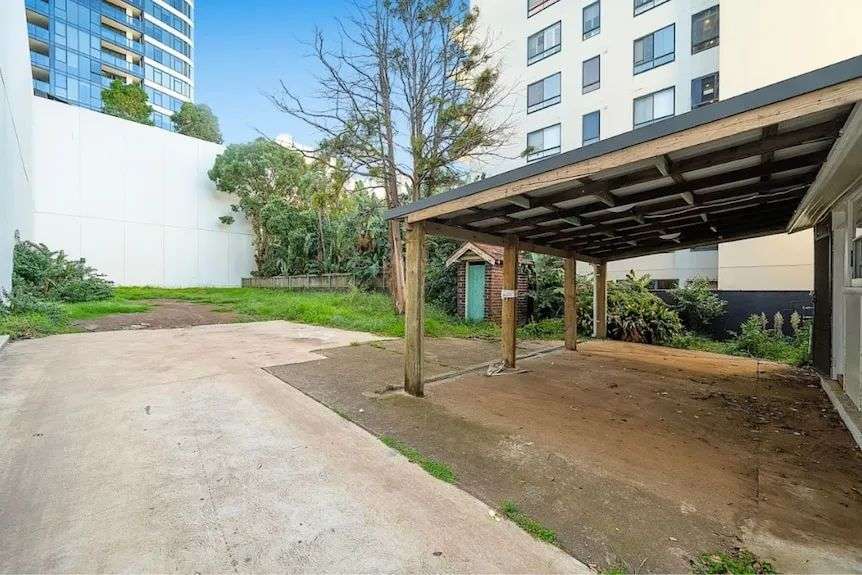 The outdoor but covered garage area of the property, with cement and grass flooring.