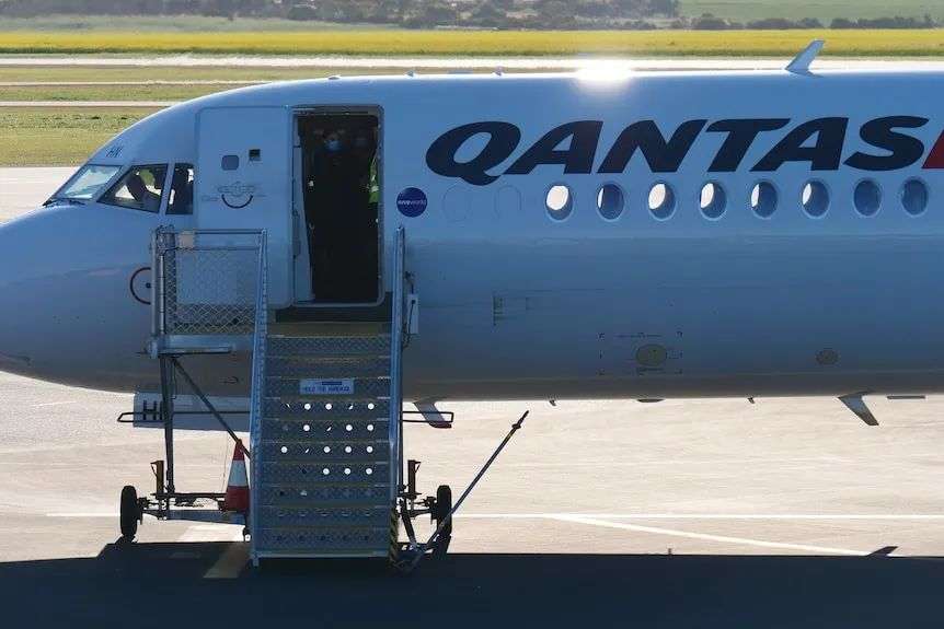 Close up shot of qantas plane with door open and stairs on tarmac