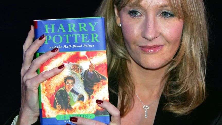 JK Rowling holding a copy of Harry Potter and the Half Blood Prince