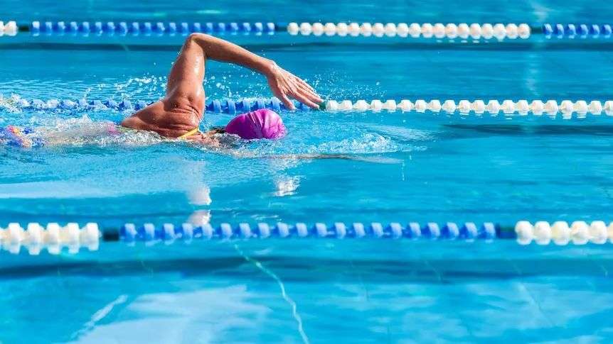 A woman in a pool swimming the freestyle stroke.