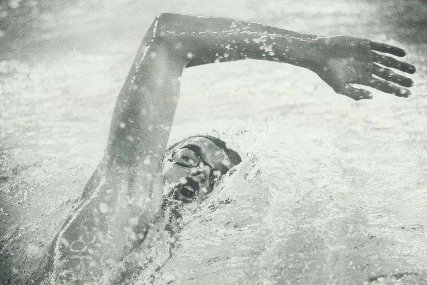 A black and white photo of a man swimming freestyle