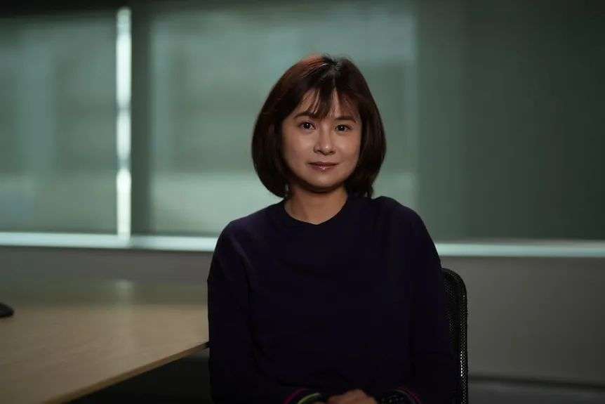 Asian woman with short brown hair sitting in an office.