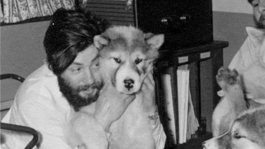 a man holds a dog close to his face and holds the dogs neck