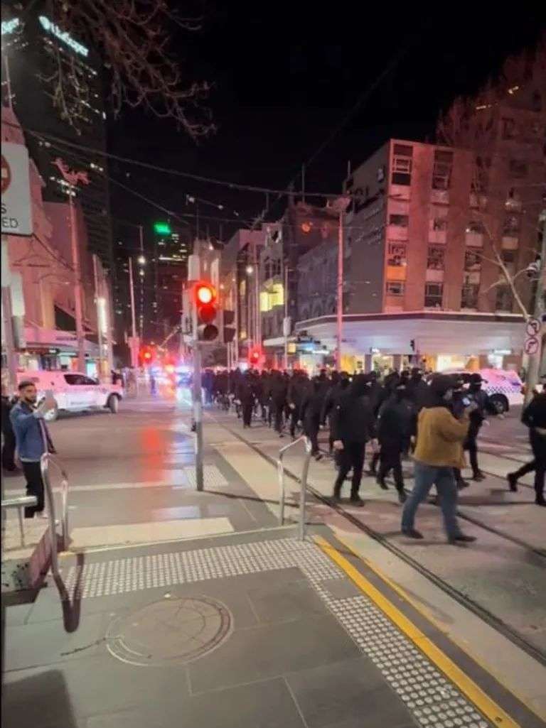 Around 100 men dressed in black paraded through the CBD at night. Picture: TikTok