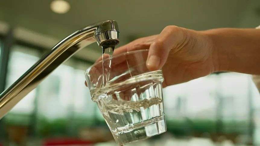 A person filling a glass with water from a tap