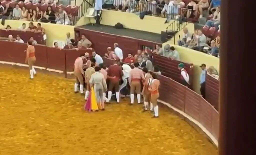 People attending to an injured bullfighter in a bullring.