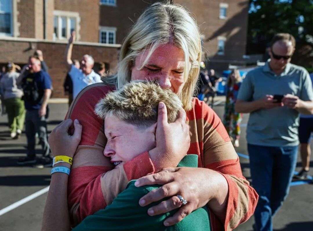 明尼苏达州明尼阿波利斯市天使报喜教堂发生枪击事件,一位母亲拥抱儿子。图片/盖蒂图片社